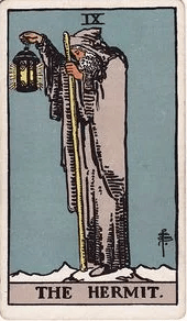 An old man in grey robes stands alone on a snowy mountain peak, holding a staff and a raised lantern with a six-pointed star inside.